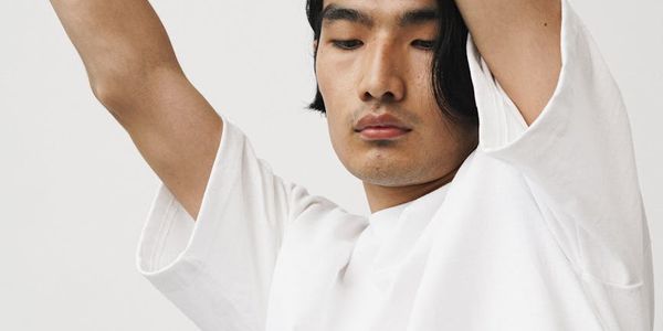 Person stretching arms wide in a spacious, minimalist room.